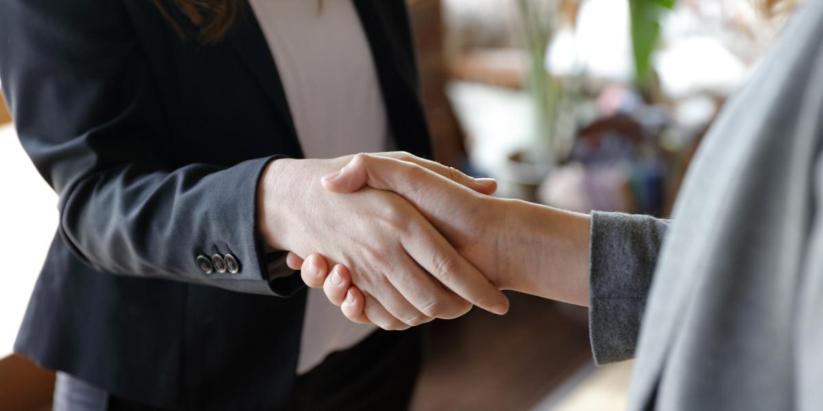 Two women shake hands. 