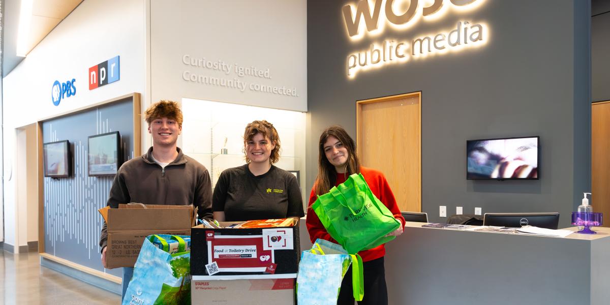 three people holding food and toiletry donations at WOSU