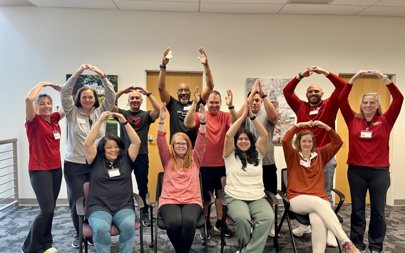 group of people signaling O-H-I-O with arms